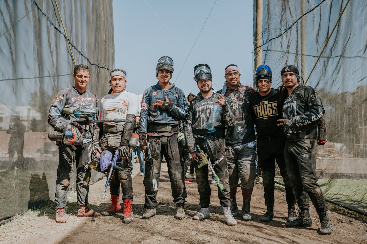 A group of men enjoying an outdoor paintball game in gear, smiling for the camera.